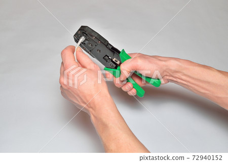 Hands of the installer of computer networks ticks crimped connec Hands of the installer of computer networks ticks crimped connec 72940152