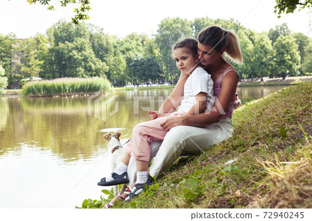young pretty caucasian mother walking with little cute daughter and dog fox terrier, lifestyle people concept young pretty caucasian mother walking with little cute daughter and dog fox terrier, lifestyle people concept 72940245