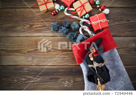 The Befana with sweet coal and candy on wooden background. Italian Epiphany day tradition. The Befana with sweet coal and candy on wooden background. Italian Epiphany day tradition. 72940446