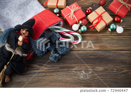 The Befana with sweet coal and candy on wooden background. Italian Epiphany day tradition. The Befana with sweet coal and candy on wooden background. Italian Epiphany day tradition. 72940447