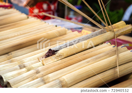 Street food market in Asia. A man sells rice in bamboo stalks 72940532
