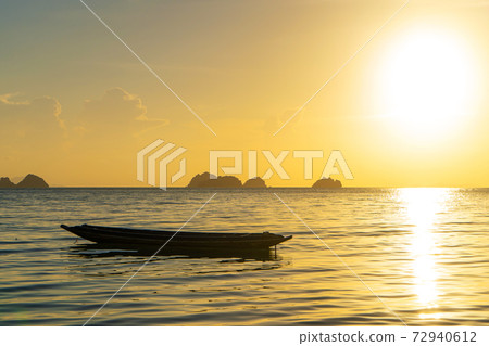 Beautiful sunset on the coast of a tropical island in Thailand, a silhouette of a boat in the ocean 72940612