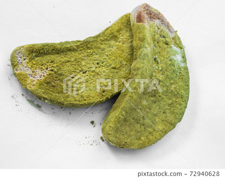 A piece of bread covered with green mold on a white background isolate 72940628