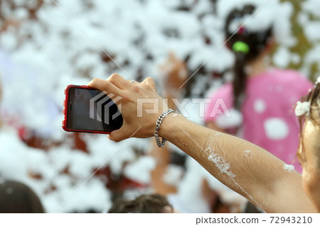 people take a selfie with a mobile phone in soapy foam at a concert people take a selfie with a mobile phone in soapy foam at a concert 72943210