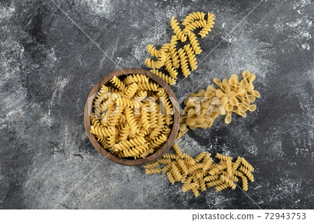Bowl of raw fusilli pasta on marble background 72943753