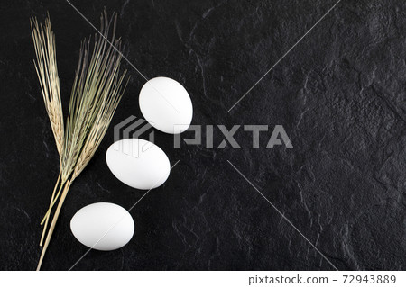Two eggs and ears of white on black background Two eggs and ears of white on black background 72943889
