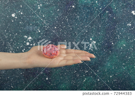 Woman hand holding a small pink doughnut 72944383