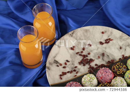Colorful sweet small doughnuts with bottles of orange juice 72944386