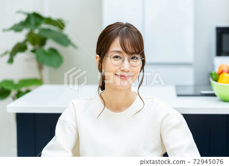 A smiling woman relaxing in the kitchen 72945076