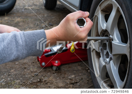 一個男人的手用十字扳手擰緊輪胎螺母 72949846