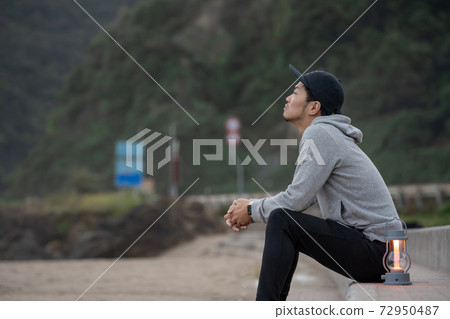 一個住在兩個地區的人，週末清晨在海灘上放鬆 72950487