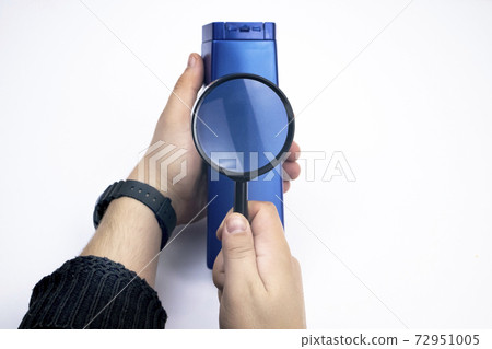 Chemical components on the shampoo label. A hand holds a blue jar and a magnifier, where the harmful ingredients of a detergent are written in close up. Place for an inscription. 72951005