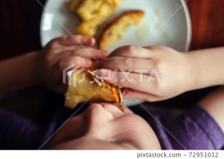 Little boy eating a piece of pineapple. Top view of a table with a plate and cut fruit. Dark treatment creates atmosphere and immersion. The concept of a rich life and connoisseurs of delicious food Little boy eating a piece of pineapple. Top view of a table with a plate and cut fruit. Dark treatment creates atmosphere and immersion. The concept of a rich life and connoisseurs of delicious food 72951012