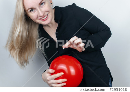 Conceptual photography. The woman holds a red ball near his belly, which symbolizes bloating and flatulence. Then she brings a needle to it to burst the balloon and thus get rid of the problem. Conceptual photography. The woman holds a red ball near his belly, which symbolizes bloating and flatulence. Then she brings a needle to it to burst the balloon and thus get rid of the problem. 72951018