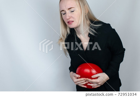 Bloating and flatulence concept. The woman holds a red balloon near the abdomen, which symbolizes bloating. Intestinal tract and digestive system. Problems with flatulence and gastrointestinal tract 72951034