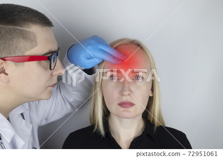 A woman holds his head with his hands. Sensation of headache, migraine and dizziness. Headaches from stress or overwork. On examination by a doctor. 72951061