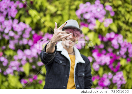 Happy cheerful handsome trendy alternative young man teenager portrait smiling on camera with coloured flower park background - diversity and youthful people with joy Happy cheerful handsome trendy alternative young man teenager portrait smiling on camera with coloured flower park background - diversity and youthful people with joy 72951603