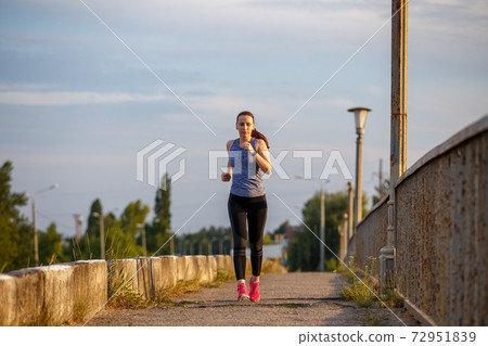 Fitness young woman running on the road in the city Fitness young woman running on the road in the city 72951839