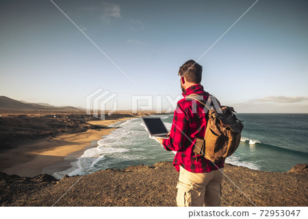 Digital nomad people smart working concept with standing man work with laptop computer and internet connection roaming in wild outdoor place with amazing beach view - travel lifestyle off grid 72953047