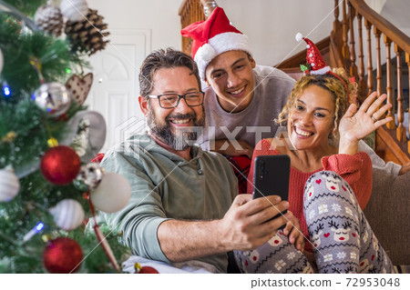 Happy family at home during christmas eve day enjoy a video phone call with friends and parents - concept of happy people and online internet technology - people and modern lifestyle having fun Happy family at home during christmas eve day enjoy a video phone call with friends and parents - concept of happy people and online internet technology - people and modern lifestyle having fun 72953048
