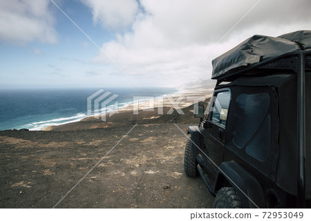Black off road car parked on the top of a valley with amazing view on a wild beach with nobody - off grid roof tent and adventure lifestyle travel concept Black off road car parked on the top of a valley with amazing view on a wild beach with nobody - off grid roof tent and adventure lifestyle travel concept 72953049
