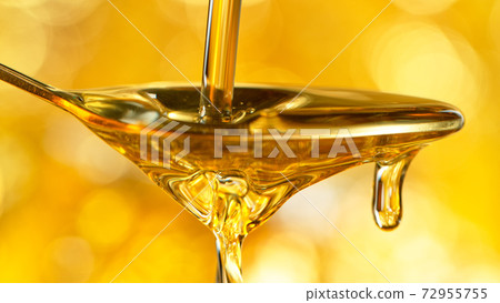 Pouring oil or honey on golden background. 72955755