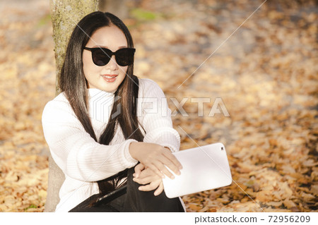 Asian beautiful woman is travel for holiday in the winter of Europe and view autumn leaves of big tree in Lausanne city at Switzerland,Vintage style and copy space. 72956209