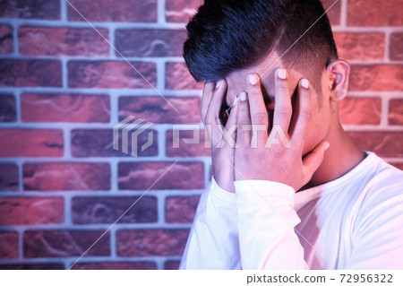 Close up of sad man covering face with hand. 72956322
