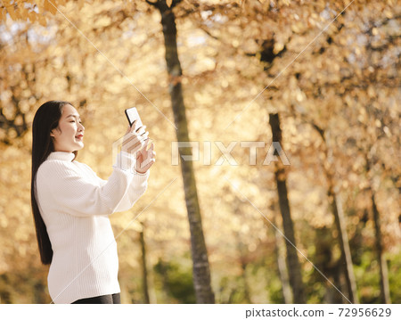 Asian beautiful woman is travel for holiday in the winter of Europe and view autumn leaves of big tree in Lausanne city at Switzerland,Vintage style and copy space. 72956629