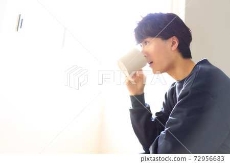 年輕人在房間裡喝飲料 72956683