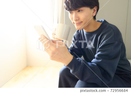A young man looking at the screen of the smartphone 72956684