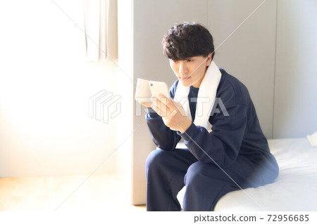 A young man looking at the screen of the smartphone A young man looking at the screen of the smartphone 72956685