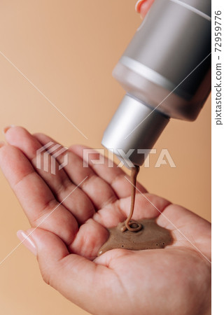 Girl pours chocolate shampoo into her hand 72959776