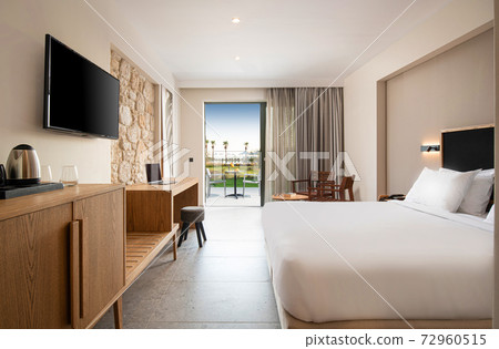 Empty light interior of contemporary hotel bedroom with beige stone wall, wooden furniture and open air terrace Empty light interior of contemporary hotel bedroom with beige stone wall, wooden furniture and open air terrace 72960515