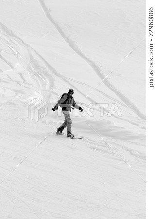 Snowboarder downhill on snowy off-piste slope after snowfall Snowboarder downhill on snowy off-piste slope after snowfall 72960886
