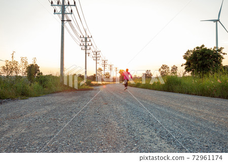 The evening sunset, The area of the wind turbine generates clean energy electricity, A woman is jogging on the road. The evening sunset, The area of the wind turbine generates clean energy electricity, A woman is jogging on the road. 72961174