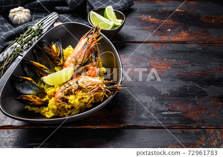 Seafood paella with prawns, shrimps, mussels. Black wooden background. Top view. Copy space 72961783