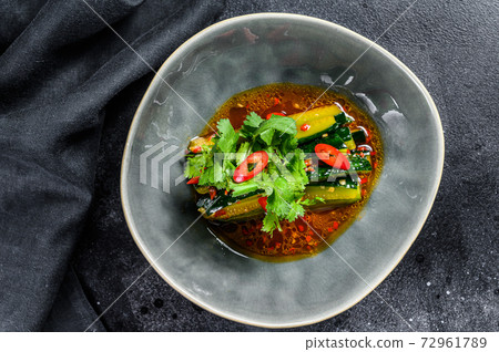 Chinese cucumber salad with chili pepper, garlic, soy sauce and sesame oil. Black background. Top view. 72961789