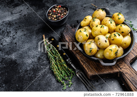Young baby boiled potato with butter in a pan. Black background. Top view. Copy space 72961888