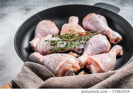 Raw organic chicken legs with spices and garlic ready to cook in a pan. White background. Top view Raw organic chicken legs with spices and garlic ready to cook in a pan. White background. Top view 72962034