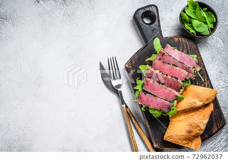 Tuna steak sandwich in a baguette with arugula. White background. Top view. Copy space Tuna steak sandwich in a baguette with arugula. White background. Top view. Copy space 72962037