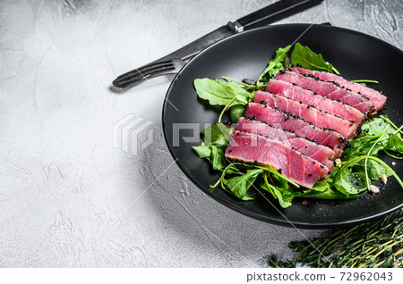 Tuna steak salad with arugula and spinach. White background. Top view. Copy space 72962043