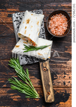 Shawarma roll sandwich in a lavash with chicken, beef, mushrooms, cheese. Dark Wooden background. Top view Shawarma roll sandwich in a lavash with chicken, beef, mushrooms, cheese. Dark Wooden background. Top view 72962191