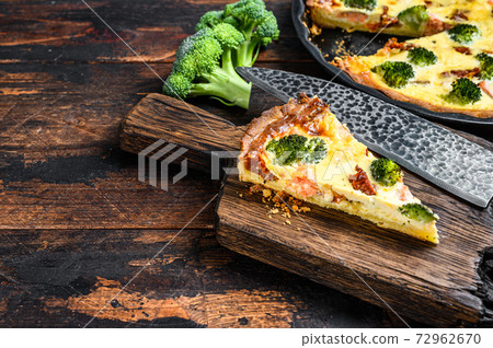 Quiche sliced tart with salmon, spinach and cream. Dark wooden background. Top view. Copy space 72962670