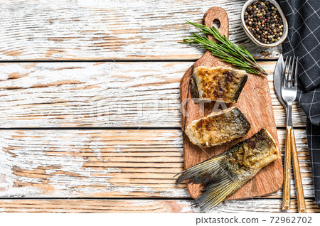 Grilled river fish silver carp on a cutting board. Wooden background. Top view. Copy space Grilled river fish silver carp on a cutting board. Wooden background. Top view. Copy space 72962702
