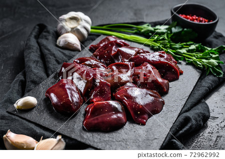 Raw Turkey liver on a stone Board. Black background. Top view Raw Turkey liver on a stone Board. Black background. Top view 72962992
