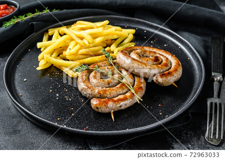 Spiral grilled sausages with a side dish of French fries. Black background. Top view Spiral grilled sausages with a side dish of French fries. Black background. Top view 72963033