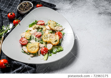Classic Caesar salad with grilled chicken breast, Parmesan, quail eggs, tomatoes and Romaine lettuce. White background. Top view. Copy space 72963175