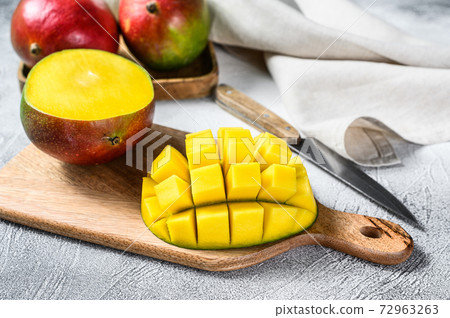 Mango fruit cut into cubes on a cutting Board. Gray background. Top view Mango fruit cut into cubes on a cutting Board. Gray background. Top view 72963263