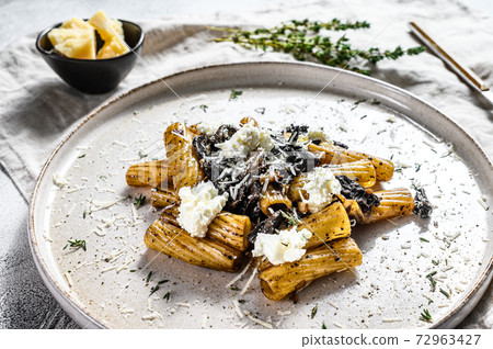 Pasta tortiglioni with black truffle and Boletus edulis, white mushroom. Gray background. Top view Pasta tortiglioni with black truffle and Boletus edulis, white mushroom. Gray background. Top view 72963427